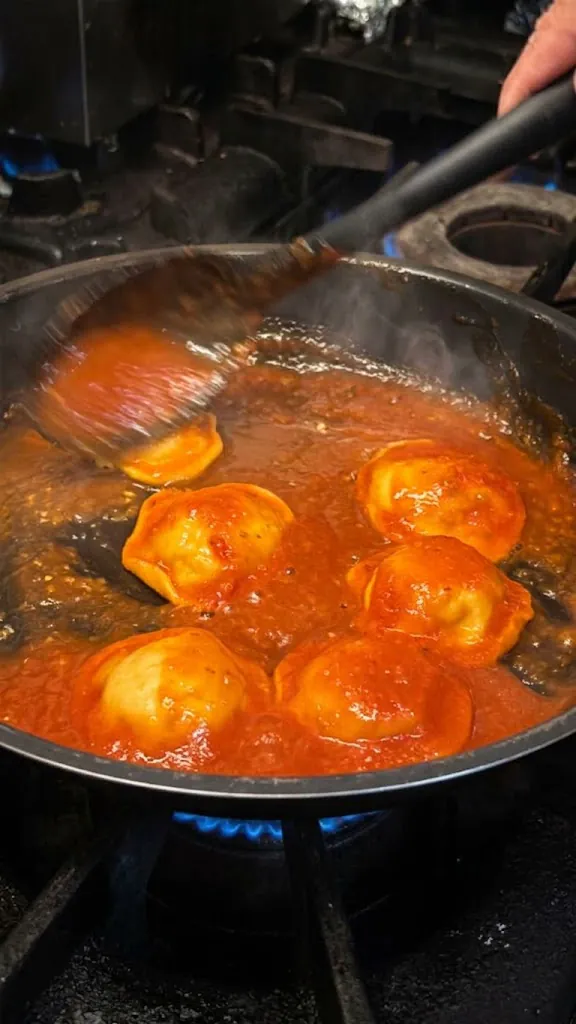 Piezas de pasta rellena en una sartén con salsa de tomate